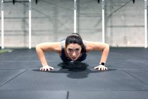 Forte déterminée jeune sportive faisant des pompes au cours de l'entraînement fonctionnel intense dans la salle de gym — Photo de stock