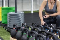 Кукурудза невизначена атлетична жінка, яка збирає важкий чайник під час підготовки до вправ з ваги під час функціональних тренувань у спортзалі — стокове фото