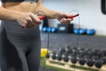 Cortar feminino magro irreconhecível em sportswear fazendo exercício com corda de salto durante o treino funcional no clube de esportes — Fotografia de Stock