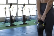 Анонимная спортсменка в спортивной одежде, выполняющая упражнения с тяжелыми гирями во время функциональной тренировки в спортзале — стоковое фото