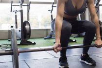 Анонімна жінка-спортсменка, яка піднімає важкий штангу під час інтенсивних функціональних тренувань у спортзалі з сучасним обладнанням — стокове фото