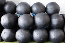 Conjunto de bolas de medicina preta para treinamento funcional empilhadas em fileiras perto da parede no clube de esportes moderno — Fotografia de Stock