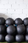 Set di palle mediche nere per un allenamento funzionale impilate in file vicino al muro nel moderno club sportivo — Foto stock