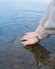 Неузнаваемая женщина-путешественница, прикасающаяся к чистой озерной воде с берега — стоковое фото