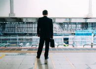 Rückansicht eines unkenntlichen Geschäftsmannes mit Rucksack, der auf dem Bahnsteig einer U-Bahn-Station in Tokio steht — Stockfoto