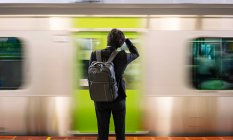Vue arrière d'un voyageur d'affaires méconnaissable avec sac à dos debout sur le quai de la station de métro à Tokyo — Photo de stock