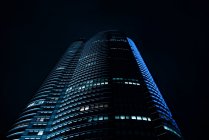 De baixo da vista de torre de arranha-céus iluminada alta na cidade grande à noite — Fotografia de Stock