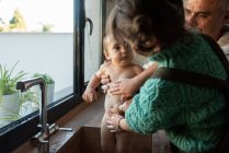 Encantado pai e filhos tomando banho bebê bonito cheio de espuma na pia na cozinha enquanto passam o tempo juntos — Fotografia de Stock
