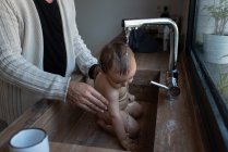 Ritaglia padre irriconoscibile lavaggio felice bambino che gioca con l'acqua dal rubinetto nel lavandino — Foto stock