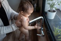 Ernte bis zur Unkenntlichkeit Vater wäscht entzücktes Kleinkind beim Spielen mit Wasser aus Wasserhahn in Spüle — Stockfoto
