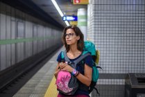 Kaukasische junge Reisende mit Rucksack wartet in einer U-Bahn-Station in Tokio auf einen Zug — Stockfoto