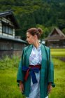 Visão lateral retrato de contemplativa jovem mulher caucasiana atraente vestindo um quimono japonês tradicional na pequena aldeia de Ainokura, Japão — Fotografia de Stock
