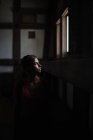 Jeune femme caucasienne regarde par la fenêtre dans Himeji Castle, Japon. Son visage est éclairé par la lumière naturelle qui entre. — Photo de stock