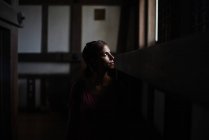 Junge kaukasische Frau blickt durch ein Fenster in Himeji Castle, Japan. Ihr Gesicht wird von natürlichem Licht erhellt, das hereinkommt. — Stockfoto