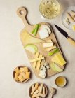 Зверху різноманітний нарізаний сир на дерев'яній дошці з грінками, розміщеними на столі — стокове фото