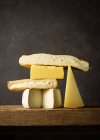 Verschiedene geschnittene Käse auf Holzbrett auf Holztisch gelegt — Stockfoto