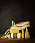 Vários queijos cortados em tábua de madeira colocados em mesa de madeira — Fotografia de Stock