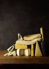 Vários queijos cortados em tábua de madeira colocados em mesa de madeira — Fotografia de Stock