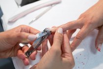 De cima de colheita anônimo beleza mestre cortando unha de mulher com cortador durante o procedimento de manicure — Fotografia de Stock