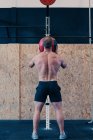 Vue arrière d'un sportif méconnaissable avec un torse nu lançant une boule de médecine lors d'un entraînement fonctionnel dans une salle de gym — Photo de stock