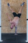Forte atleta maschio con busto nudo che si bilancia sul braccio in stand mentre fa esercizi durante l'allenamento funzionale — Foto stock