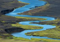 From above of picturesque landscape of bright blue river flowing among volcanic terrain in Iceland — Stock Photo