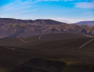 Vue panoramique route vallonnée verdoyante entourée de formations rocheuses rugueuses vallée sous dans un ciel bleu clair sans nuages — Photo de stock