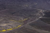 Вид на горбисту вердиктну дорогу в оточенні грубих кам'янистих утворень долини під безхмарним яскраво-блакитним небом — стокове фото