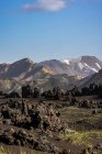 Сценический вид грубых скалистых вулканических образований в окружении холмистой сухой горы — стоковое фото