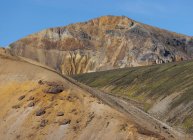 Espectacular paisaje de interminable terreno rocoso áspero con pendientes secas y vegetación aleatoria ubicada bajo cielo azul claro en Islandia - foto de stock