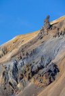 Захватывающий пейзаж бесконечной скалистой местности с сухими склонами и случайной растительностью, расположенной под ясным голубым небом в Исландии — стоковое фото