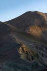 Захватывающий пейзаж бесконечной скалистой местности с сухими склонами и случайной растительностью, расположенной под ясным голубым небом в Исландии — стоковое фото