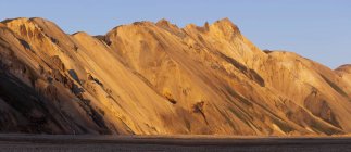 Magnifico scenario di montagne rocciose con cime illuminate dalla luce del sole in terreni desertici accidentati in Islanda — Foto stock