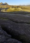 Великолепный пейзаж скалистых вулканических гор с вершинами, освещенными солнечным светом на пересеченной местности пустыни в Исландии — стоковое фото