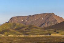 Magnífico paisaje de montañas rocosas con picos iluminados por la luz del sol en terrenos desérticos en Islandia - foto de stock