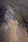 Живописный вид холмистой зеленой дороги в окружении грубых скалистых образований долины — стоковое фото