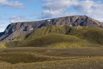 Великолепный пейзаж скалистых гор с вершинами, освещенными солнечным светом на пересеченной местности пустыни в Исландии — стоковое фото