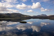 Захватывающие дух пейзажи все еще спокойного озера, отражающего ясное голубое небо и окруженного скалистыми зелеными холмами в мирных высокогорьях Исландии — стоковое фото