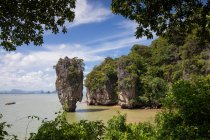 Вид на скелясті круті скелі та скелі вкриті тропічним лісом, обмитим спокійною морською водою під ясним блакитним небом у Пхукет Таїланд. — стокове фото