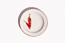 Top view composition of bowl with hot peppers with green stem placed on white background — Stock Photo