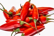 Zusammensetzung von oben mit roten frischen exotischen Paprikaschoten, die als Gewürz oder Gewürz zum Würzen von Lebensmitteln auf weißem Hintergrund verwendet werden — Stockfoto