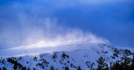 Захватывающий вид грубой горы со снегом под ярким туманным небом зимой под солнечным светом — стоковое фото