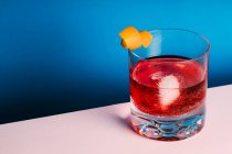 Bicchiere di cocktail alcolico amaro Negroni servito con ghiaccio e buccia d'arancia su superficie chiara — Foto stock