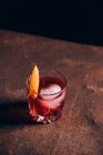 Glass of refreshing alcoholic Negroni cocktail garnished and orange peel and placed on table amidst barman tools — Stock Photo
