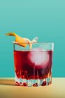 Glass of bitter alcoholic Negroni cocktail served with ice and orange peel on light surface — Stock Photo