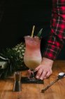 Ernte gesichtslose Person bereitet köstlichen erfrischenden Pina Colada Cocktail auf dem Tisch serviert — Stockfoto