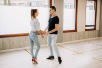 Талантливая пара, исполняющая бальные танцы во время репетиций в светлой просторной студии с зеркалом во время занятий — стоковое фото