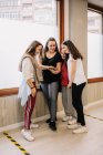 High angle of young smiling female dancers gathering in hall and watching video of dance on smartphone after lesson — Stock Photo