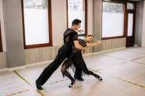 Пара танцоров в элегантной одежде, исполняющих бальные танцы во время занятий в современной студии — стоковое фото