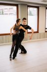Couple de danseurs talentueux se déplaçant gracieusement tout en répétant la danse de salle de bal dans le hall pendant la leçon — Photo de stock